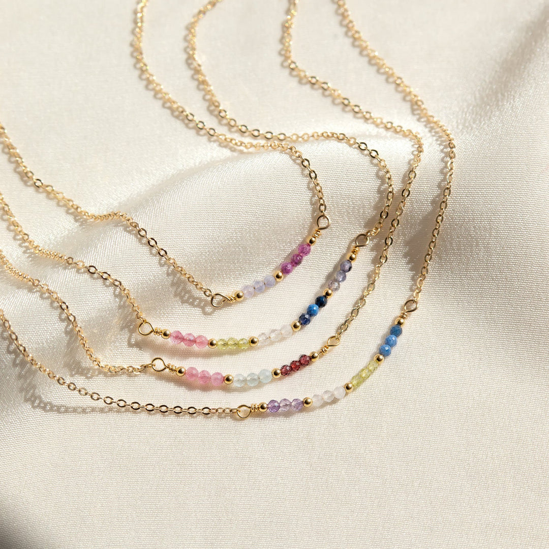 Set of gold necklaces with colorful beads on a beige fabric background