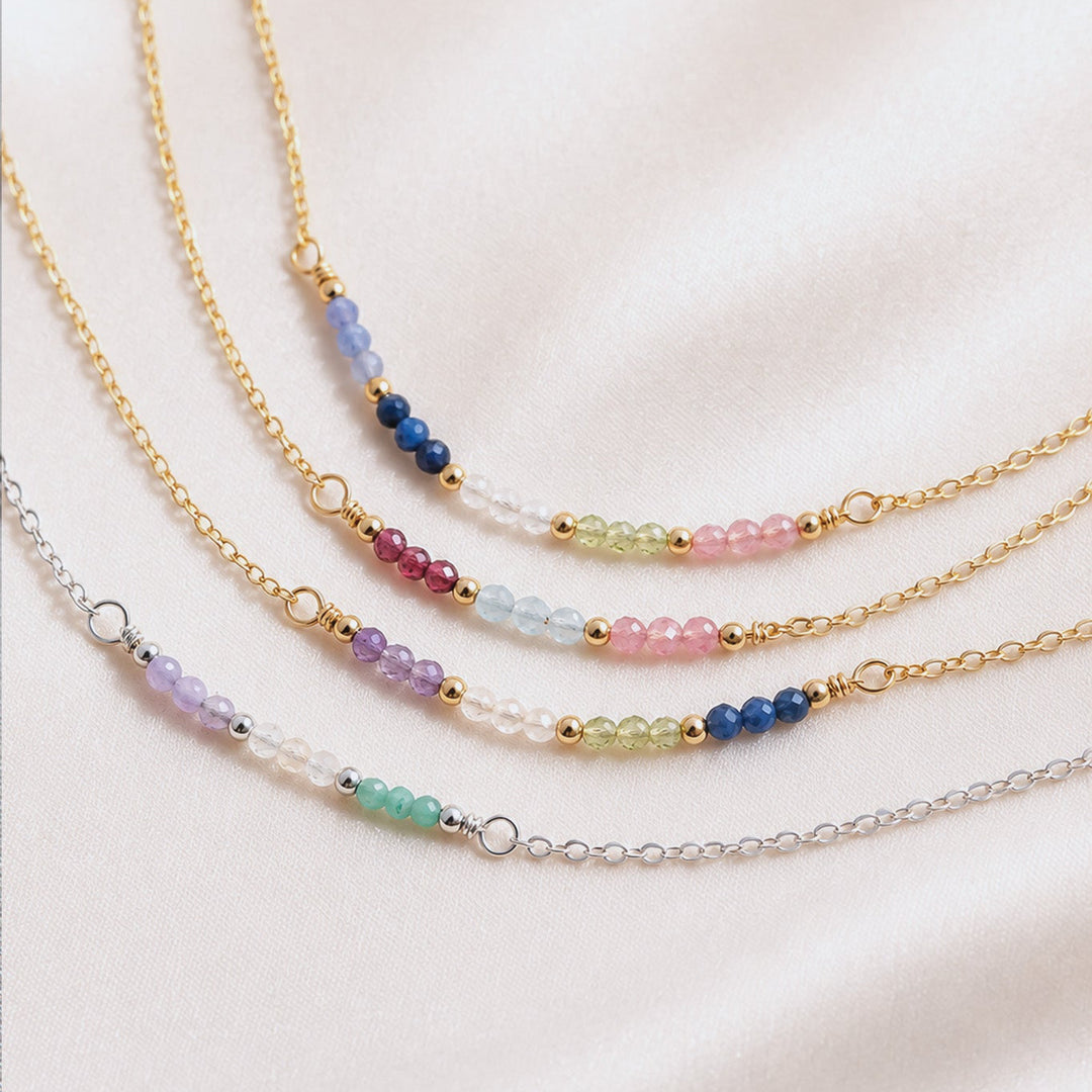 Three beaded necklaces on a light pink fabric background