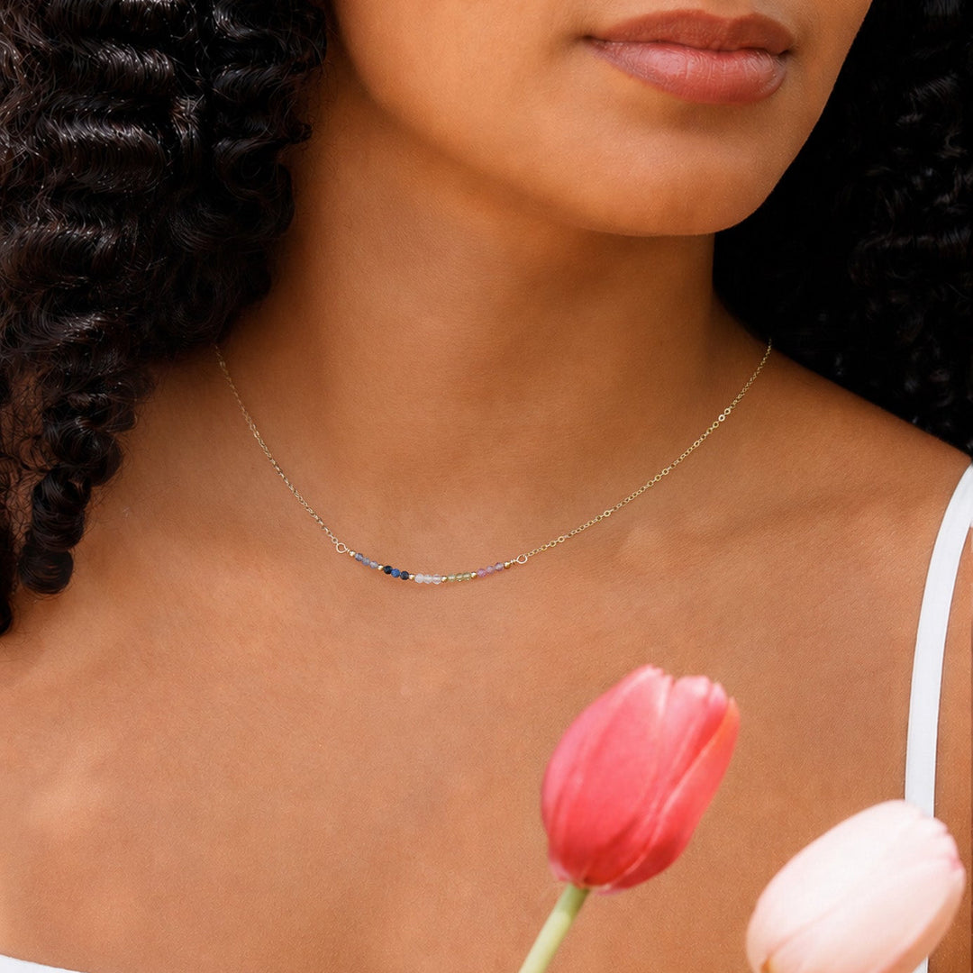 Woman wearing a delicate necklace with pink tulips in the foreground