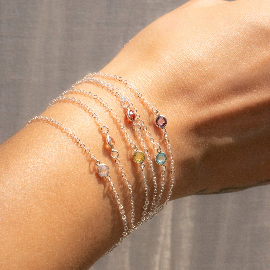Close-up of a wrist wearing multiple colorful beaded bracelets against a neutral background