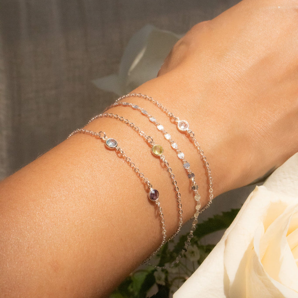 Close-up of a wrist wearing multiple delicate bracelets with a blurred background