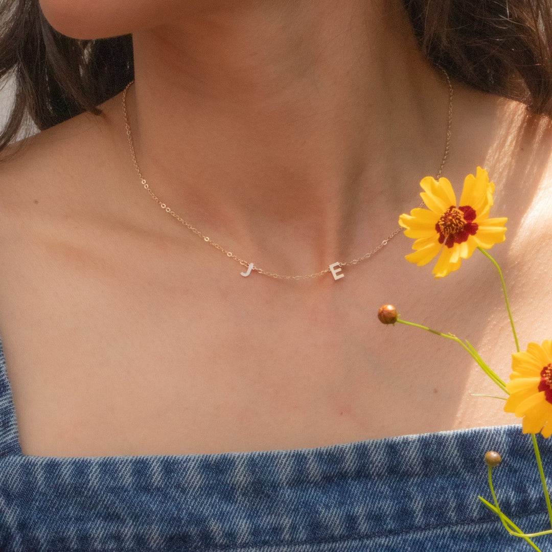 Close-up of a person wearing a delicate necklace with a yellow flower in the foreground