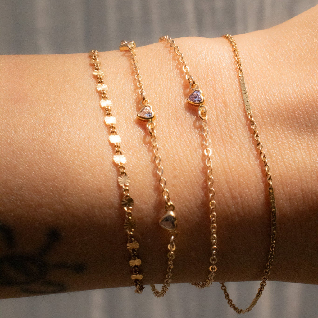Gold bracelets on a wrist with a neutral background