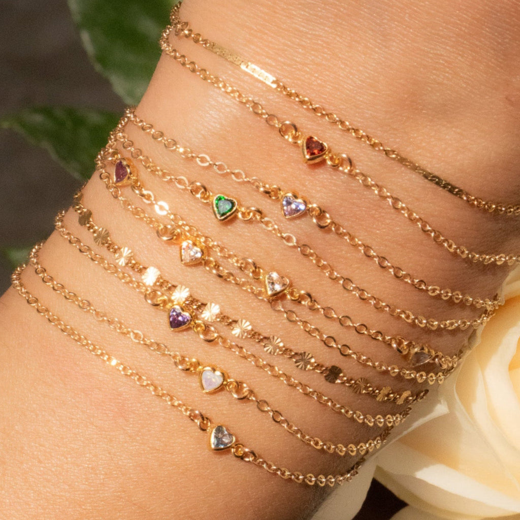 Gold bracelet with gemstones on a wrist, surrounded by flowers