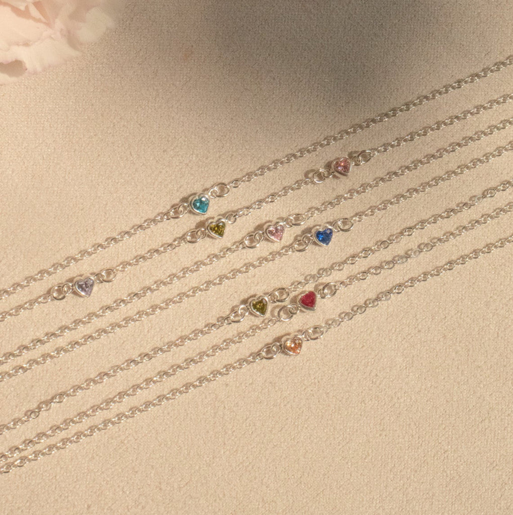 Set of delicate silver bracelets with gemstones on a neutral background