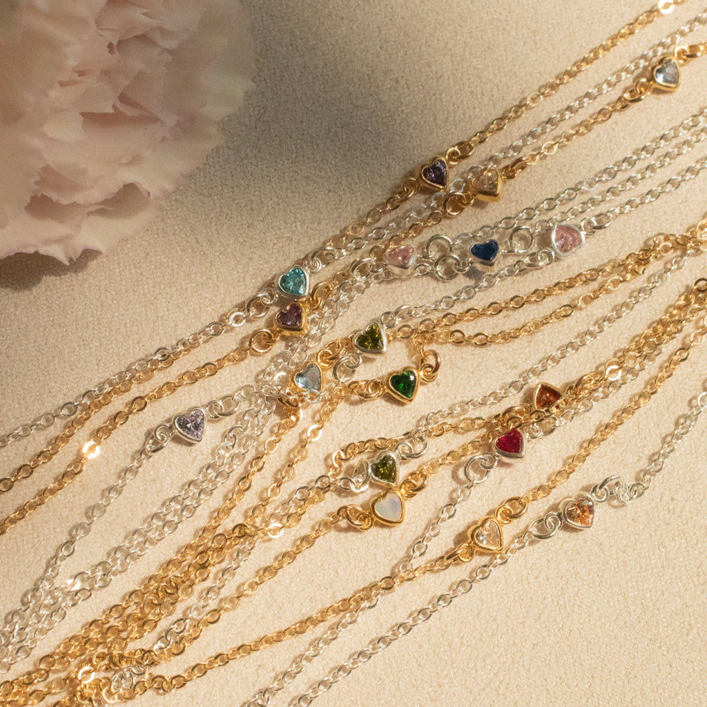 Gold bracelets with heart-shaped gemstones on a textured surface
