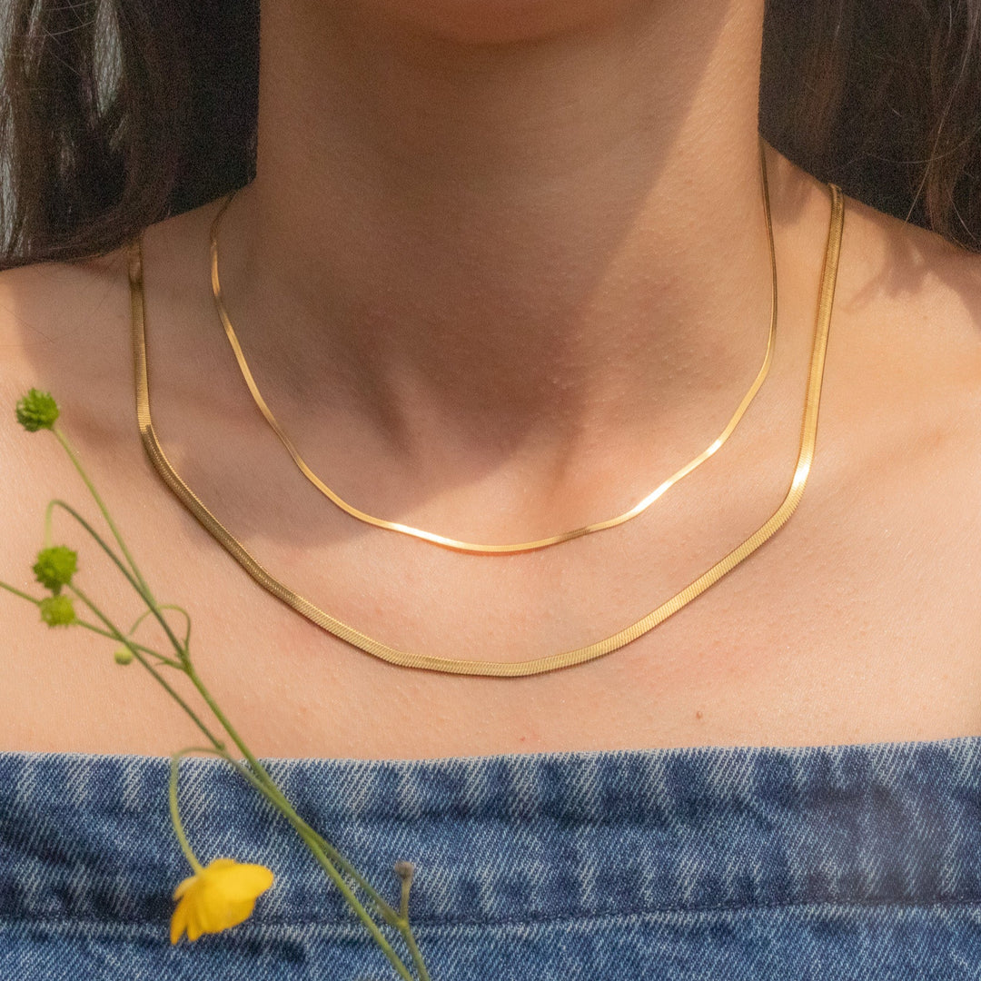 Person wearing a gold necklace with a blurred background