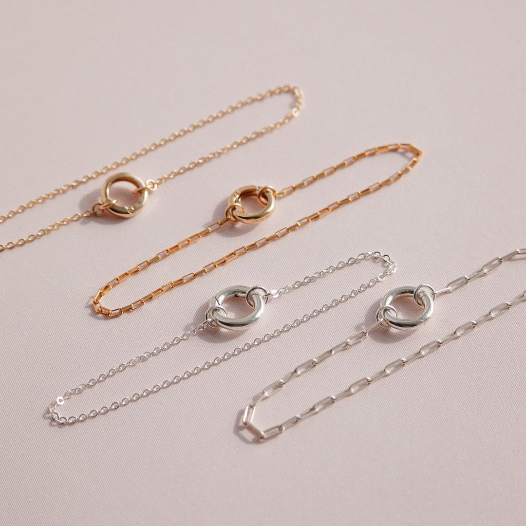 Two gold and one silver chain necklace on a light pink background