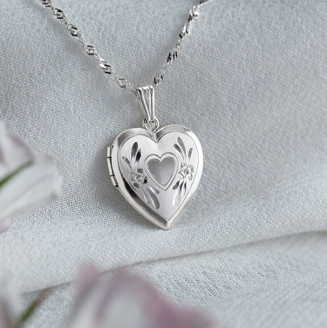 Silver heart-shaped locket on a chain with a soft white background