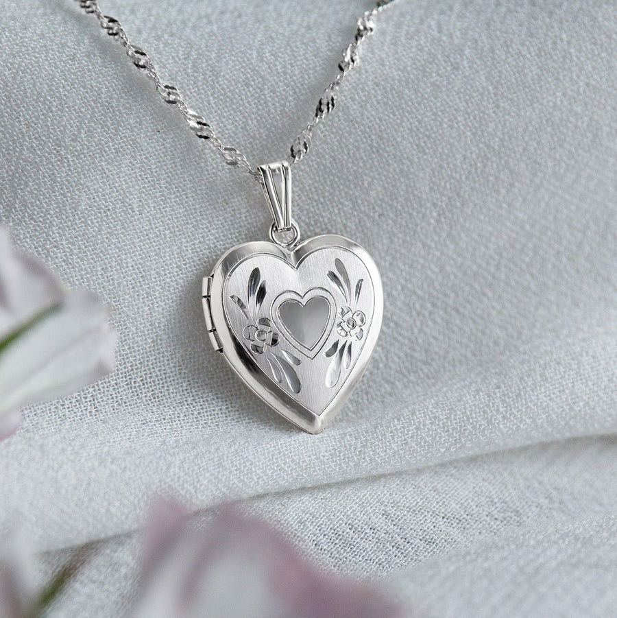 Silver heart-shaped locket on a chain with a soft white background