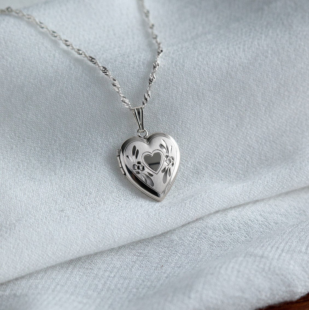 Silver heart-shaped locket necklace on a light fabric background