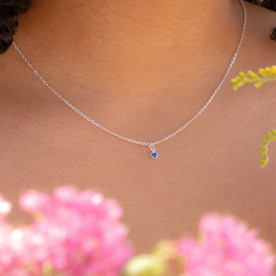 Necklace with a blue pendant worn by a person, with flowers in the foreground