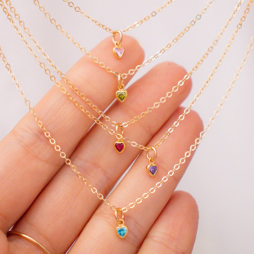 Gold necklaces with colorful gemstones on a hand against a white background