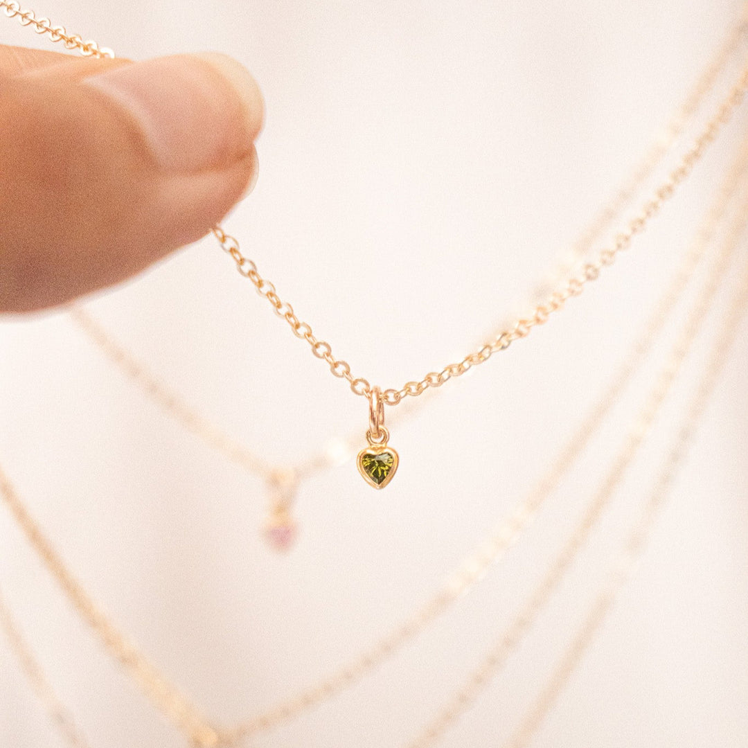 Gold necklace with a heart-shaped pendant on a white background