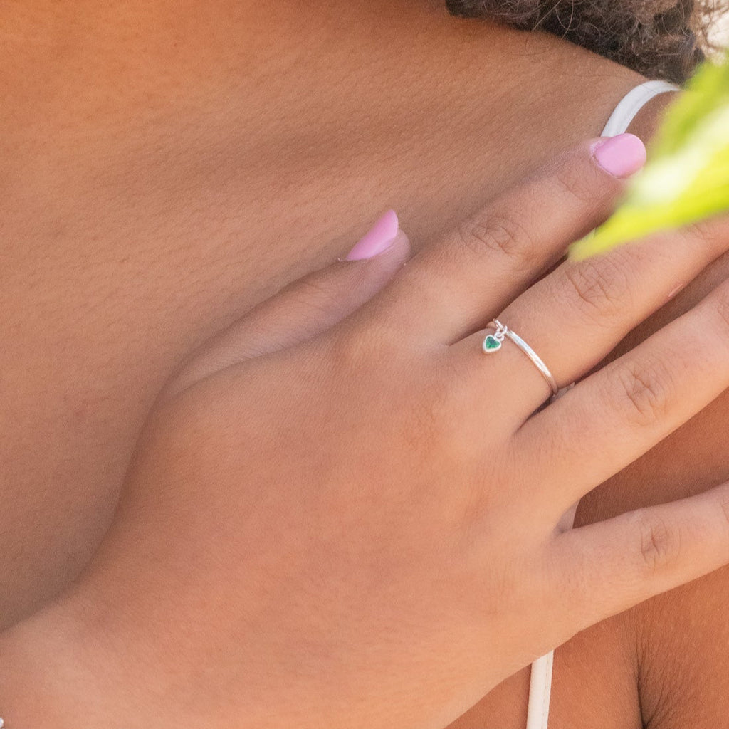 Close-up of a hand with a ring, pink flowers in the background