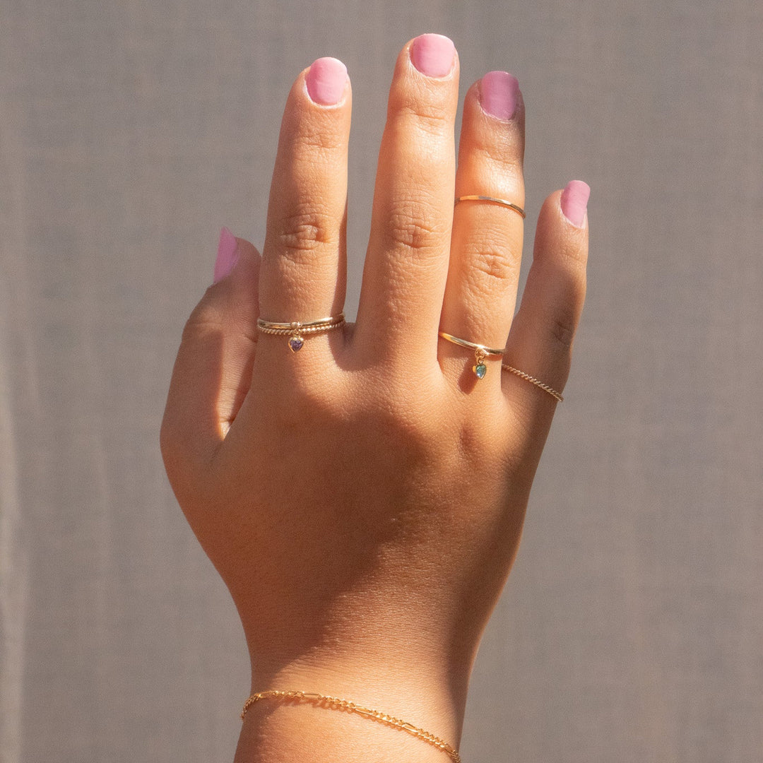 Hand wearing two gold rings with a plain background