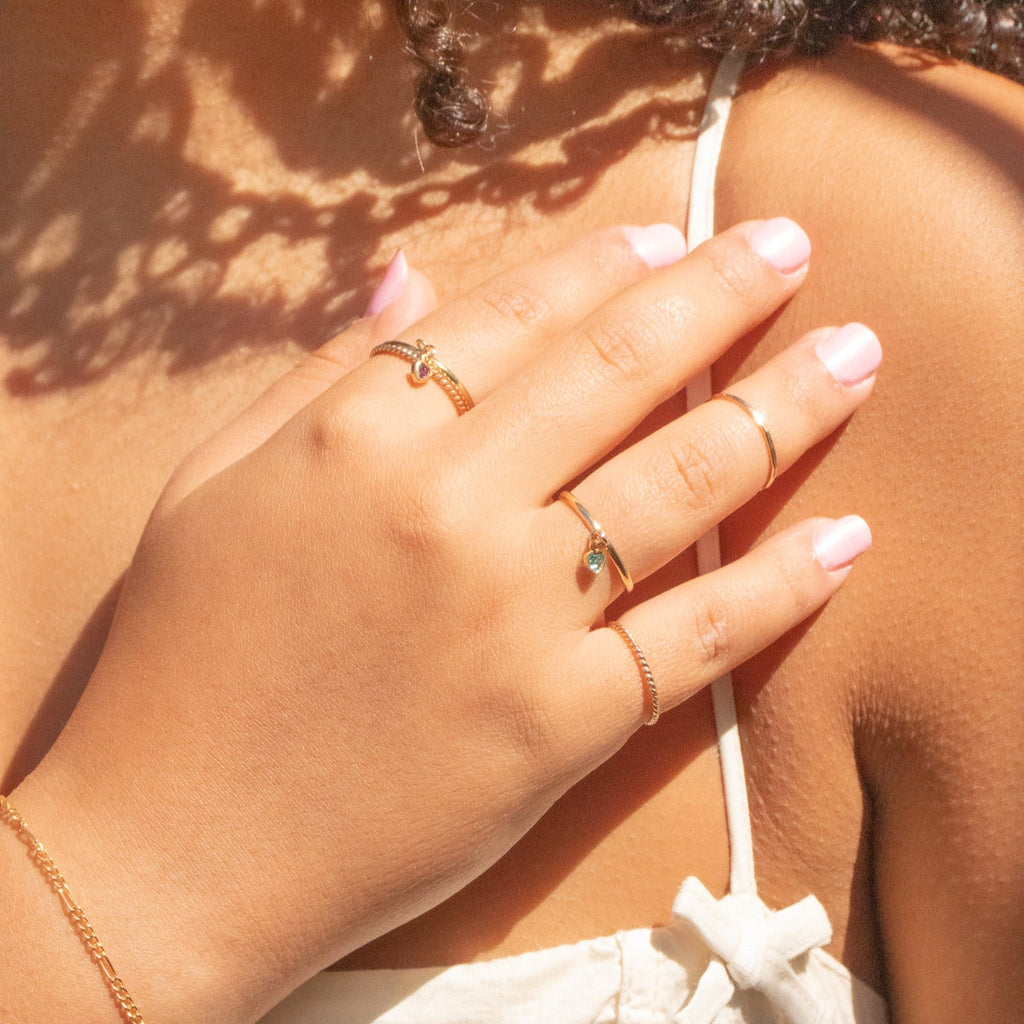 Close-up of a hand with rings on a shoulder, with sunlight casting shadows.