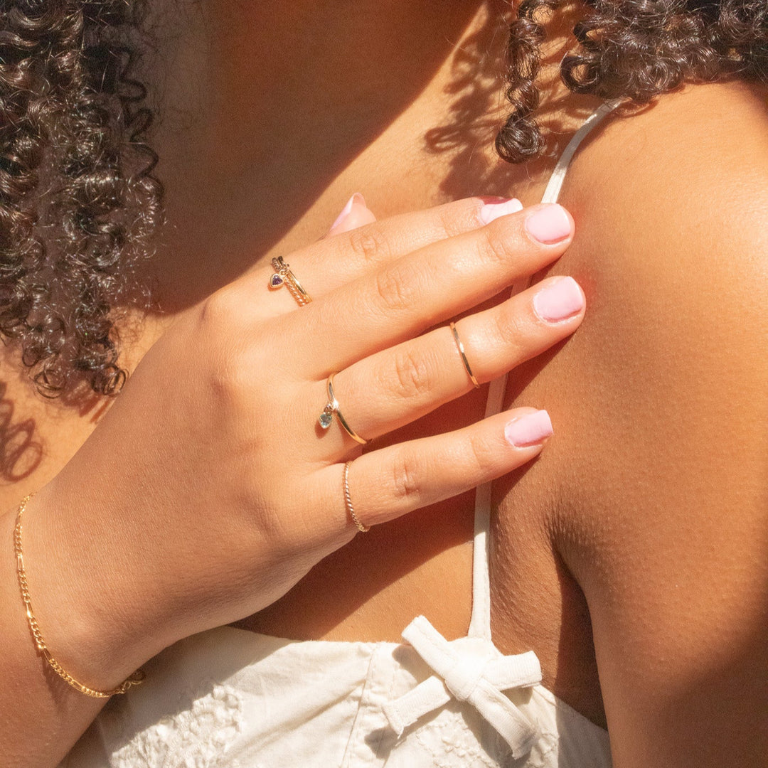 Close-up of a person with curly hair wearing multiple rings on their hand.