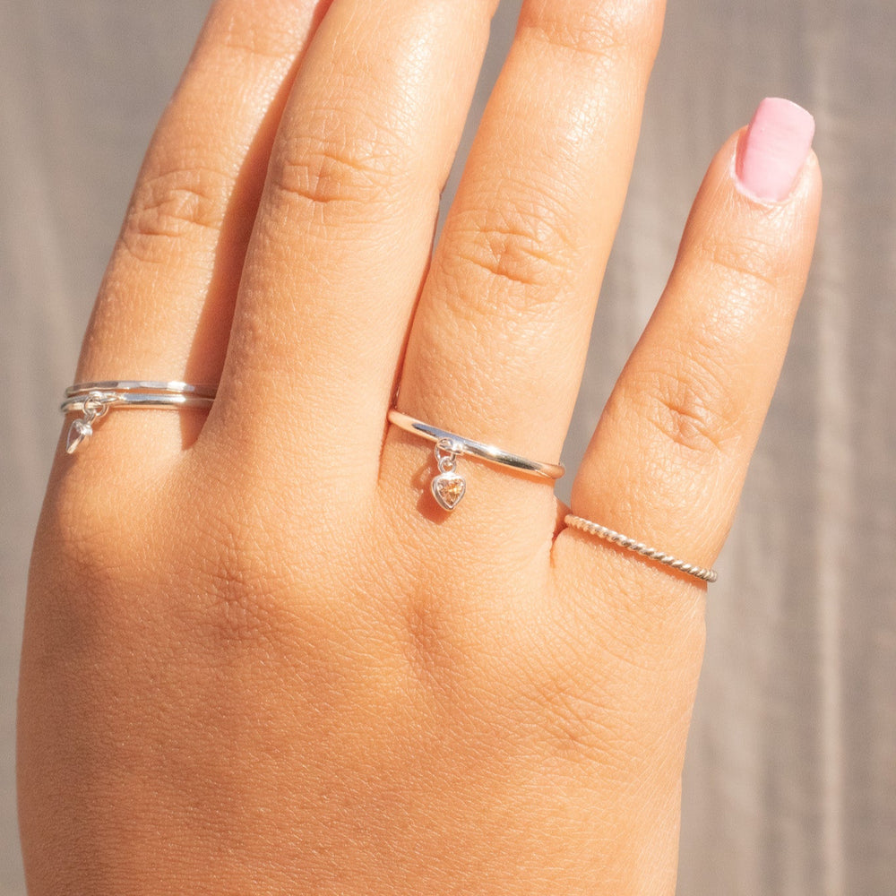 Hand wearing two silver rings with a plain background